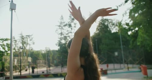 Woman Stretching Arms Overhead in an Urban Park