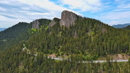 Road Passes and Meanders Among Hills Covered with Forests Against the Background of an Cloudy Sky