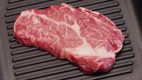 Raw Steak on Black Grill Pan Close Up