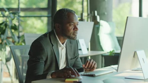 Happy Attractive African American Man Working on the Computer Smiling in the Office at His Desk