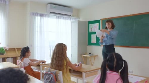 Adorable student learn with teacher in classroom at elementary school.
