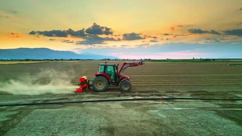 Tracteur travaillant dans un champ entouré de terres agricoles - Vue aérienne 2K