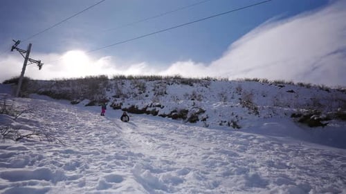 Mutter rodelt im Schnee, während Tochter Winterurlaub im Skigebiet in den Anden genießt