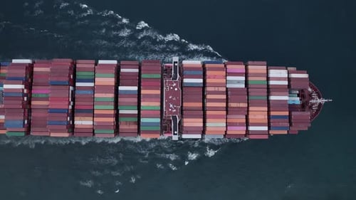 Aerial top view of a loaded container cargo vessel traveling over ocean.
