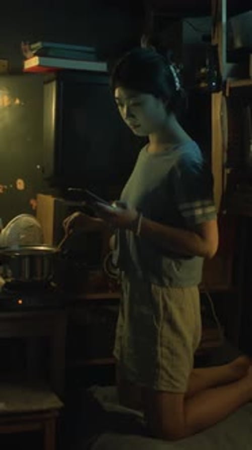 Woman Kneeling by Stove Using Phone