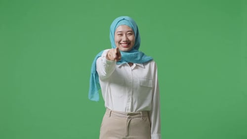 Asian Muslim Woman Smiling And Touching His Chest Then Pointing At You In The Green Screen