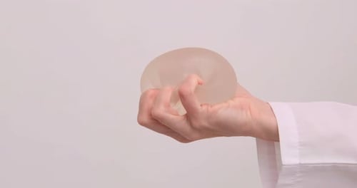 Hand Holding Silicone Breast Implant in Hospital