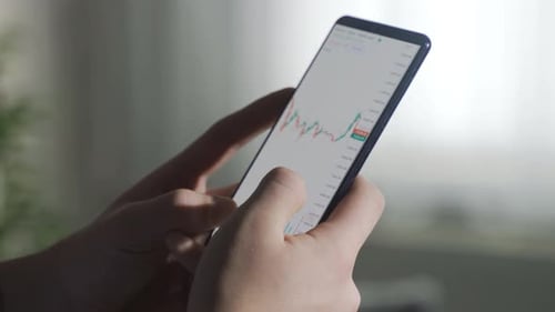 Vue rapprochée des graphiques du marché boursier et des cryptomonnaies depuis le téléphone.