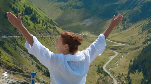Woman Raising Arms Enjoying Success on Mountain Top