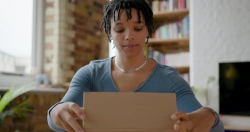 Young Woman Opens Brown Box at Desk