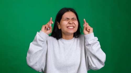 Fingers Crossed Young Woman in a Studio Shot with Fingers Crossed Expressing Hope Wish and Faith for