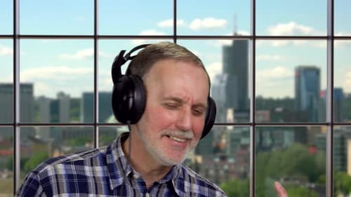 Senior Man Singing with Headphones in City Apartment