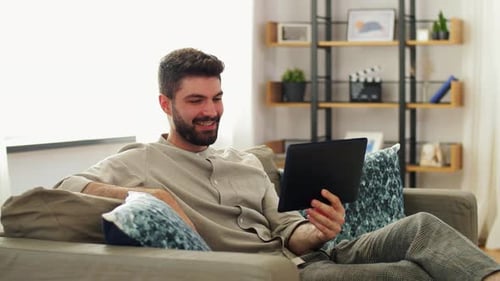Young Man Using Tablet on Sofa at Home