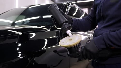 A Car Mechanic Polishing a Black Car Wash Wax and a Polishing Machine