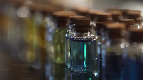 Small glass bottle row blue liquid vial picked up with two fingers