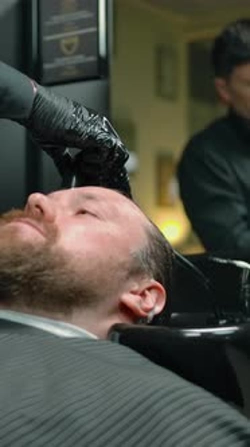 Barber Rinses Man's Hair in Barber Shop
