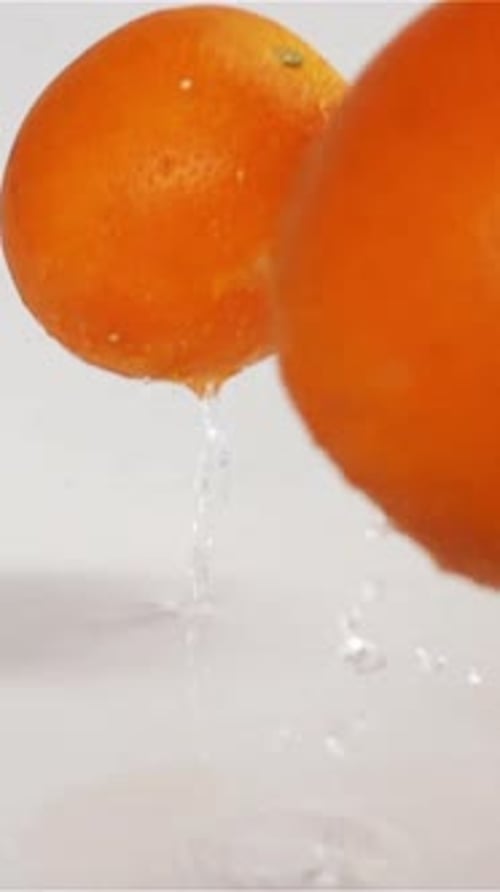 Vertical of Oranges Falling and Bouncing on Grey Wet Surface
