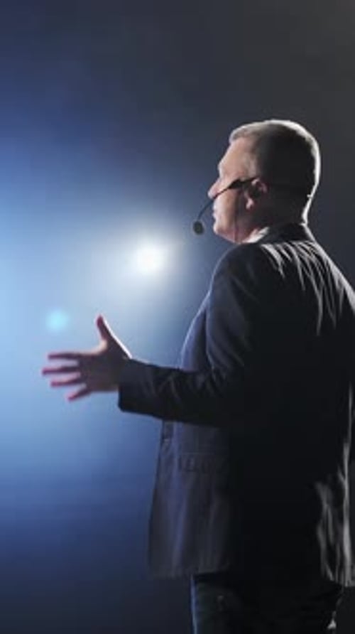 Man Wearing Suit and Jeans Speaks at Podium