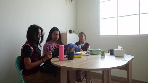 Asian Mother Preparing Lunchbox And Tumbler For Her Daughter Before Going To School