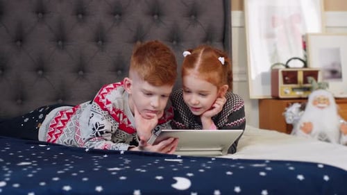 Children Lying on Bed Watching Tablet at Home