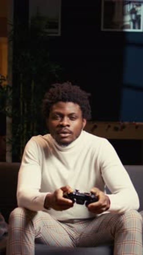 Vertical Video Gamer Using Controller to Beat Game on Gaming Console Relaxing on Couch