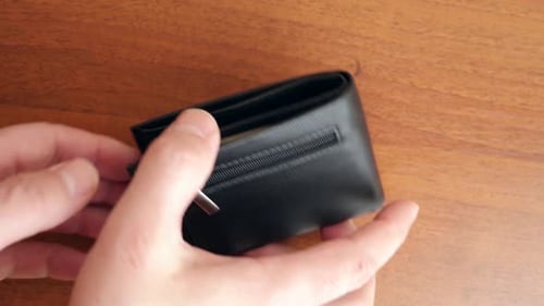 Hands Opening Leather Wallet revealing US Currency