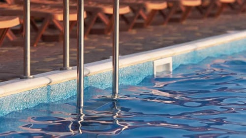 Blick von oben auf den Swimmingpool mit klarem Wasser im Urlaub auf Sonnenuntergang-Hintergrund
