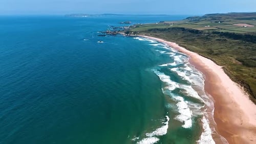 White waves rolling on the sandy beach at the coast of Ireland.