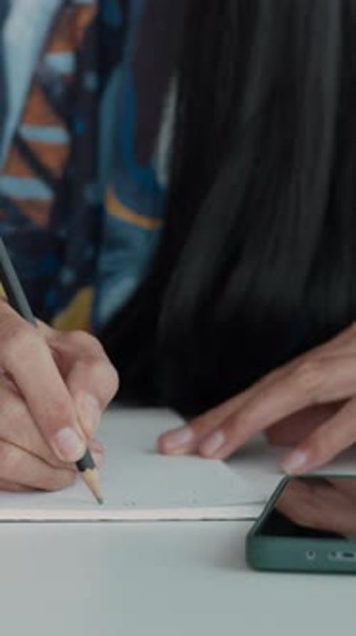 Person writing in notebook with pencil close up