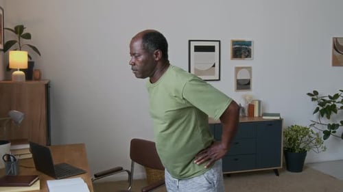 Senior Man Doing Physical Exercises while Taking Break from Work on Laptop