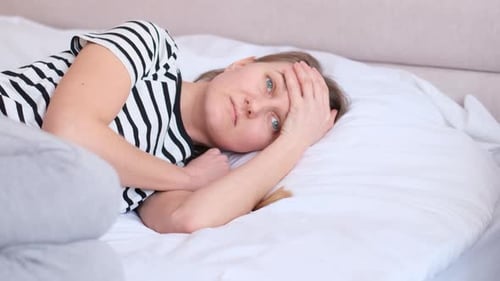 Woman Lies in Bed with Possible Headache