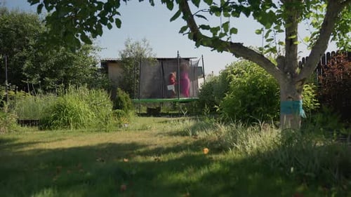 Child and young adult jumping on trampoline in garden