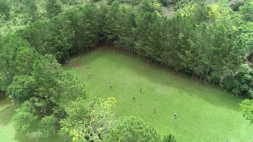 People playing a soccer match on a rural soccer field in an open area.