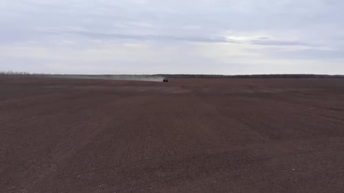 Blue tractror planting sunflower with red planter on the cultivated field in Ukraine