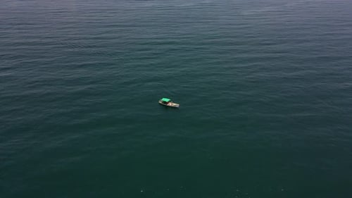 Aerial drone shot of a fisher boat surrounded by the calm and infinite beauty of the ocean.