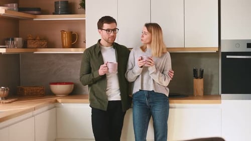 Young Couple Talking and Drinking Coffee in Kitchen