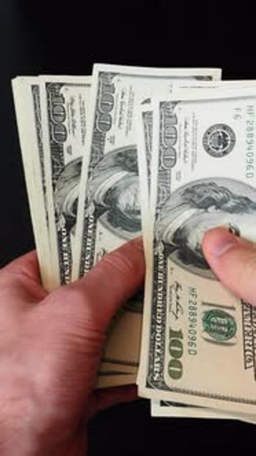 Close up of male hands holding and counting US dollar banknotes. Vertical video