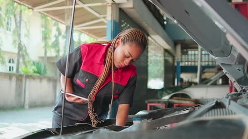 A black female automotive mechanical worker checks EV car at a fixing garage.