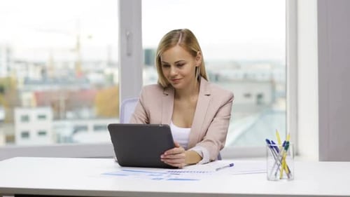 Woman Using Tablet at Desk in Bright Office
