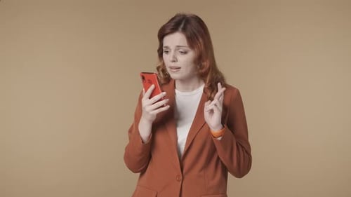 Medium Isolated Video of a Woman Holding a Smartphone in Her Hand Crossing Fingers Waiting for the