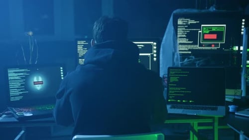 Ein erfahrener Hacker arbeitet intensiv auf mehreren Bildschirmen in einem dunklen Raum und konzentriert sich auf Aufgaben