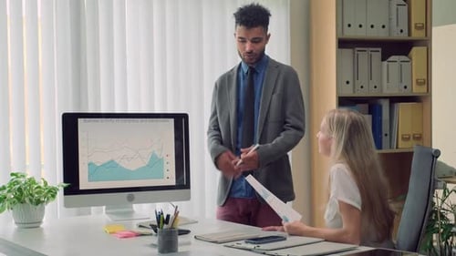 Economist Discussing Growth Indicators with Colleague Standing next to Chart
