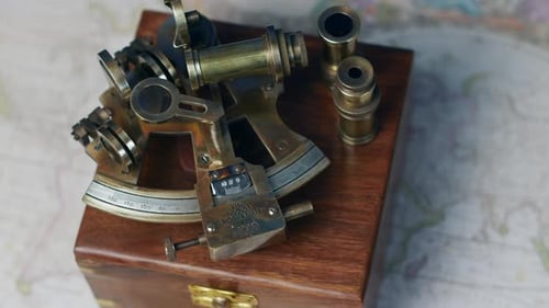 An antique nautical sextand with a rose wood box on a vintage world map
