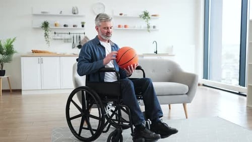 Smiling man holding basketball in a wheelchair indoors