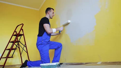 Professional repairman renovating the room. Handsome painting master doing room renovation.