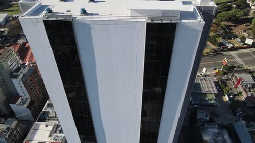 Aerial tilt up shot of modern gigantic building tower in Buenos Aires City against blue sky and sunl