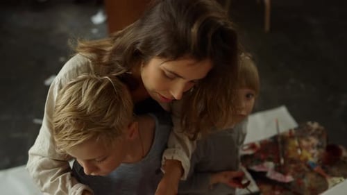Careful Mother Showing Painting Tools to Son in Modern Studio. Little Girl