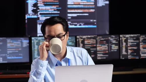 Man Working at Laptop with Code on Multiple Screens