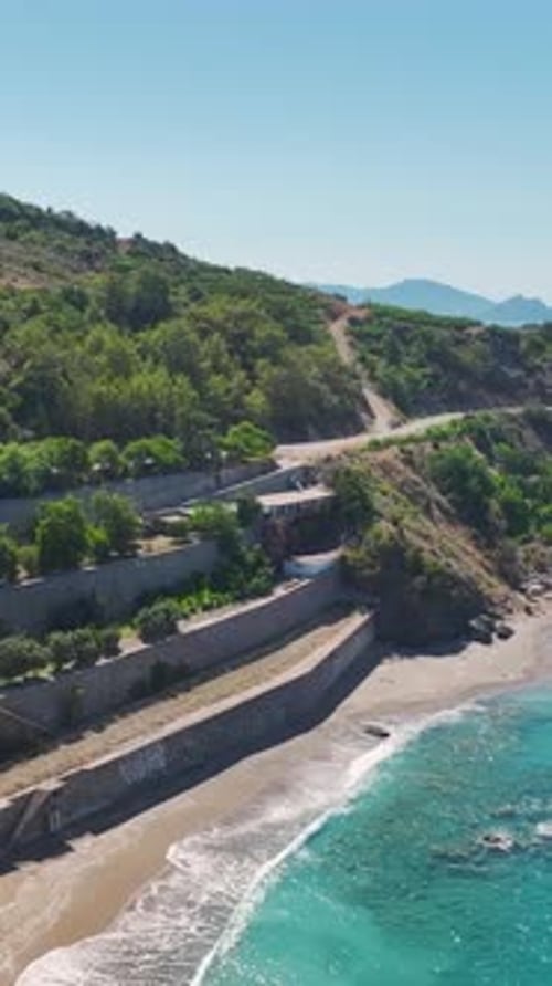 Vertical Video Aerial View of the Azure Sea and Rocky Beach Showcasing Stunning Coastal Beauty and