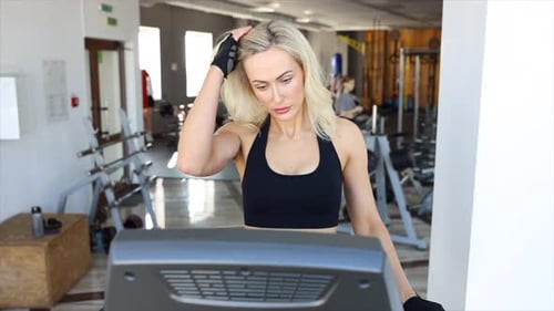 Determined sportswoman running on treadmill in modern gym